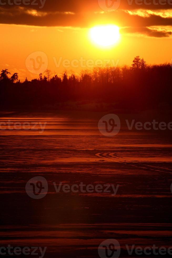 sole che tramonta dietro un lago ghiacciato del saskatchewan foto