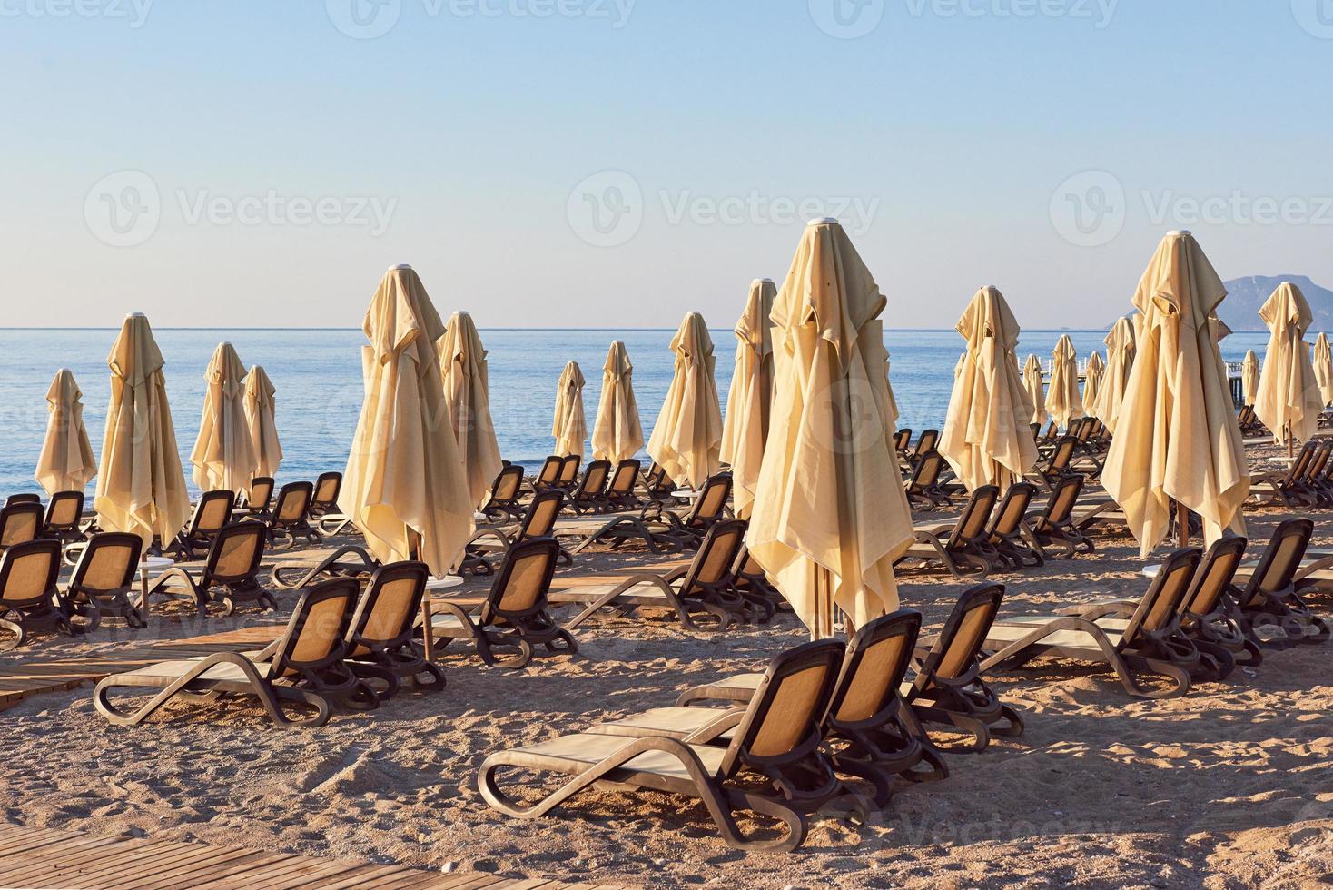 vista panoramica della spiaggia sabbiosa privata con lettini e parasokamy sul mare e sulle montagne. ricorrere. foto