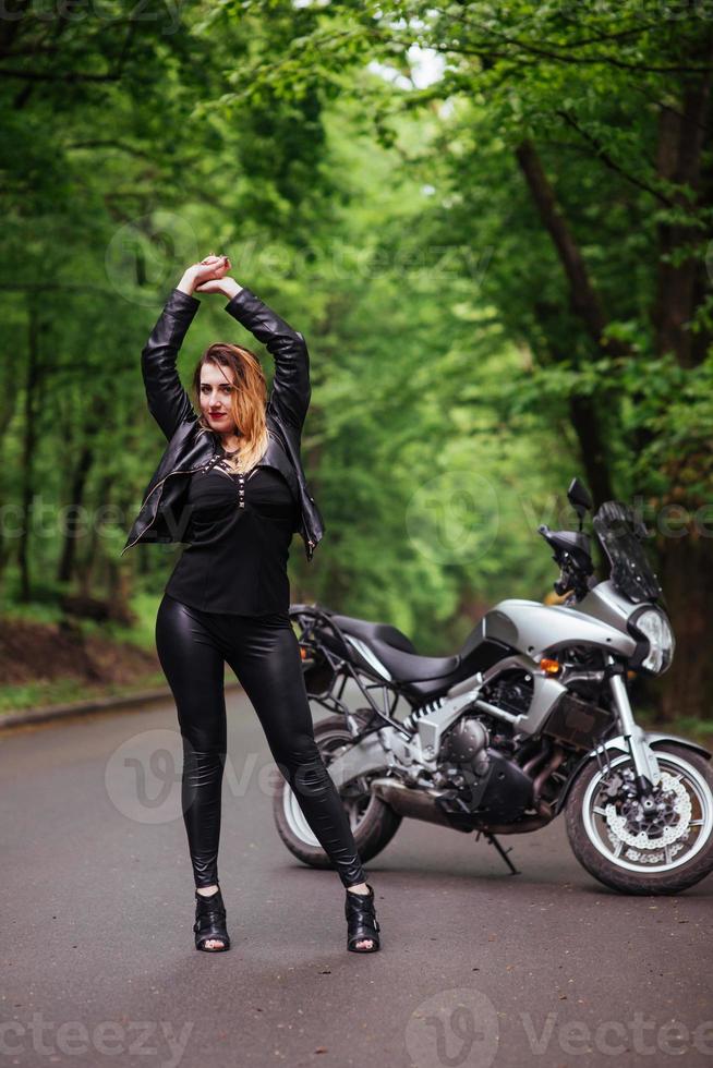 un'attraente ragazza sexy su una moto sportiva in posa all'esterno foto