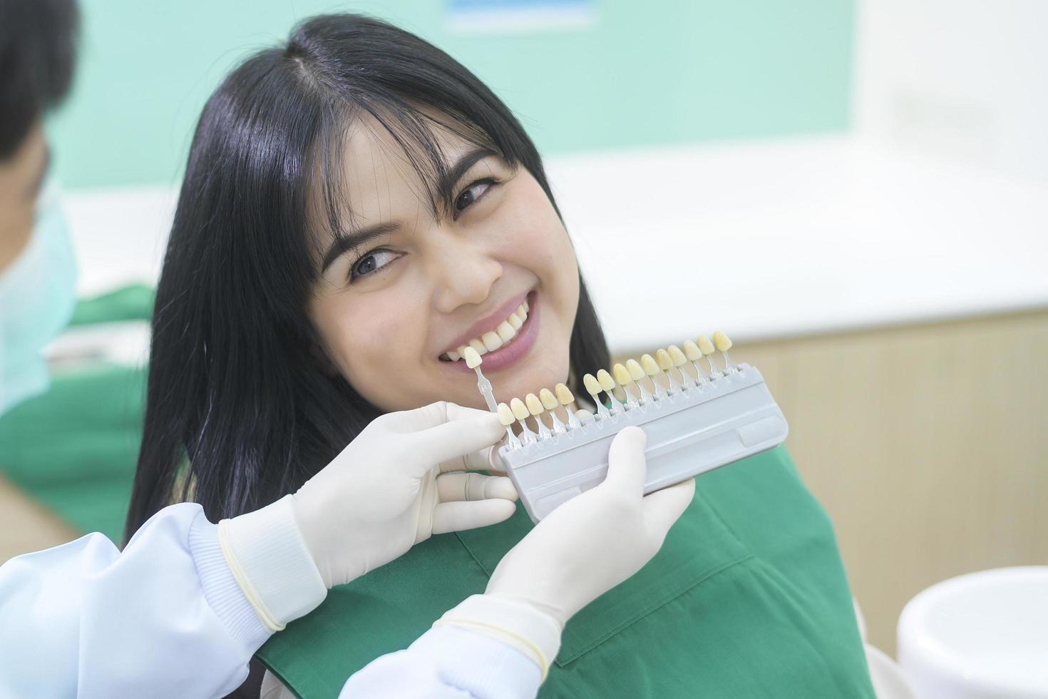 un dentista sta esaminando i denti di una paziente di sesso femminile utilizzando il livello di sbiancamento foto