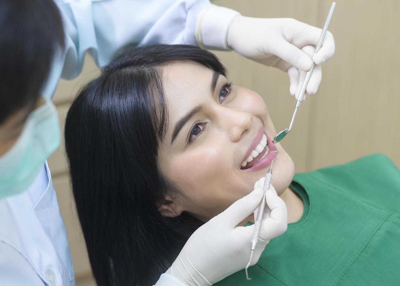 una giovane donna che ha i denti esaminati dal dentista in clinica odontoiatrica, controllo dei denti e concetto di denti sani foto