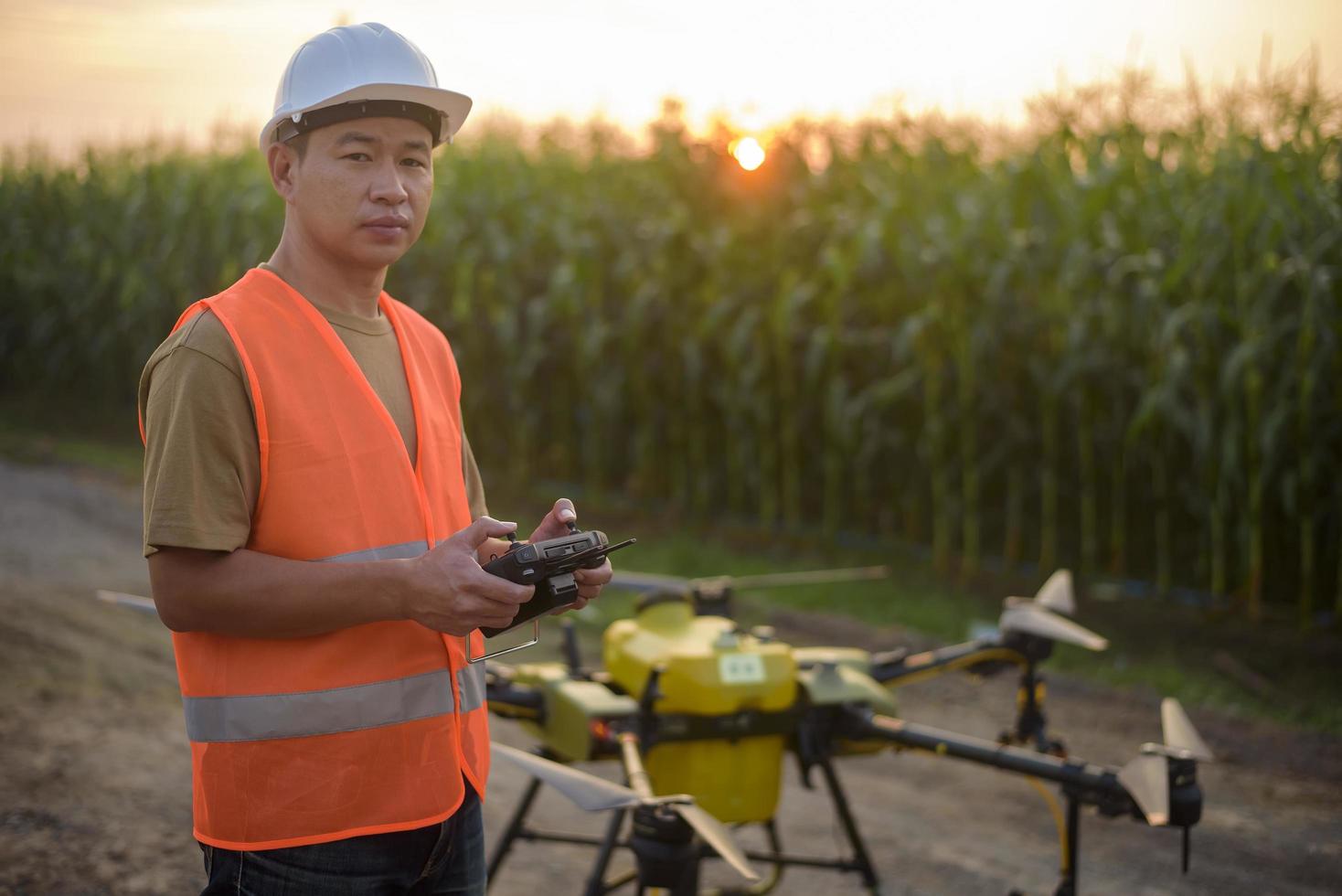 ingegnere maschio che controlla i droni che spruzzano fertilizzanti e pesticidi su terreni agricoli, innovazioni ad alta tecnologia e agricoltura intelligente foto