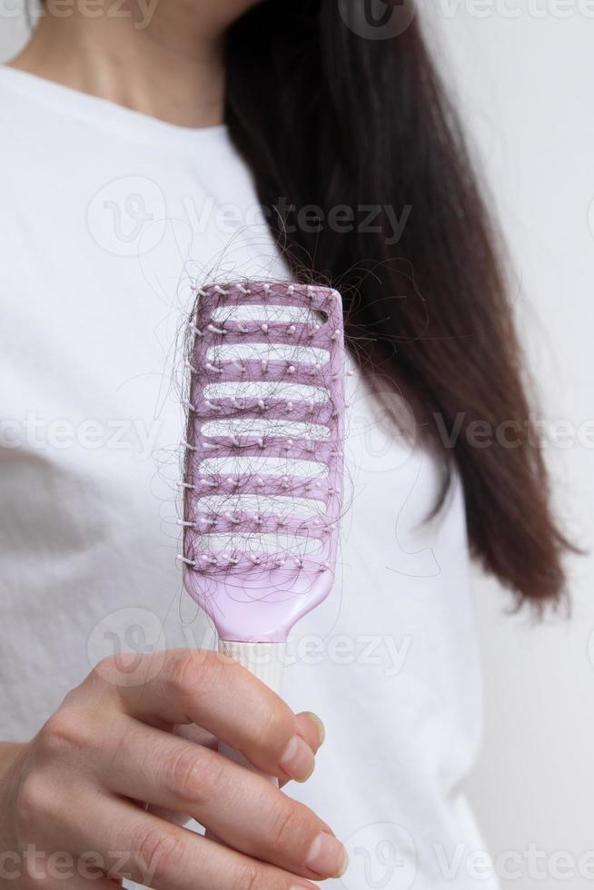 pettinare con i capelli persi. capelli aggrovigliati e che cadono, cura per il concetto di capelli lunghi foto