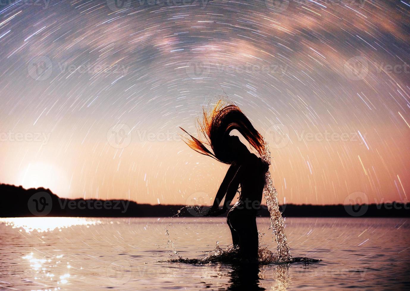 donna sullo sfondo dell'acqua al cielo notturno. fantastico il cielo stellato e la via lattea foto