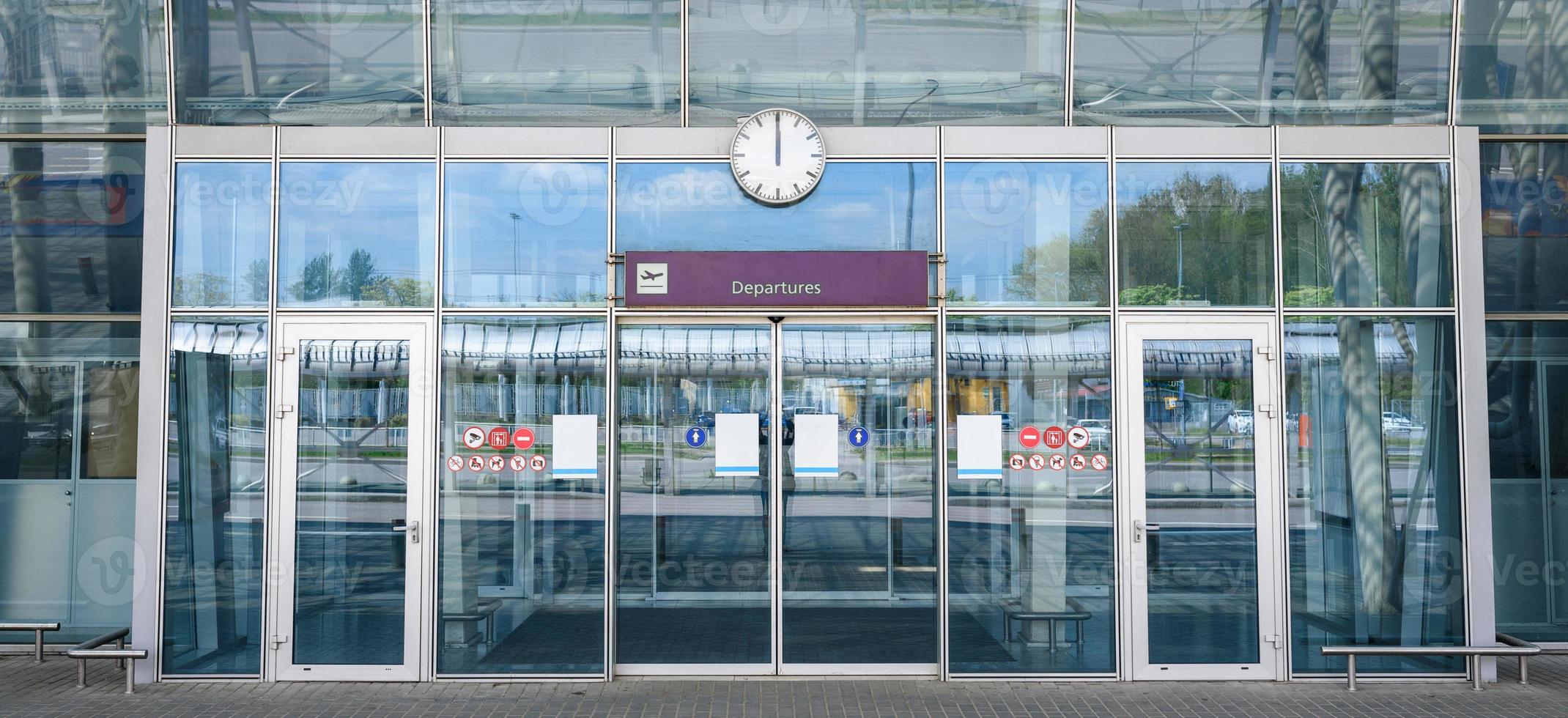 porte di vetro chiuse dell'aeroporto con un cartello di partenze foto