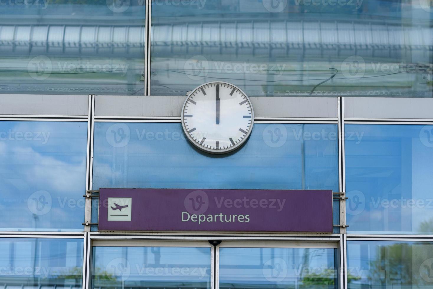 primo piano di un orologio sopra le porte chiuse dell'aeroporto in vetro con un cartello delle partenze foto