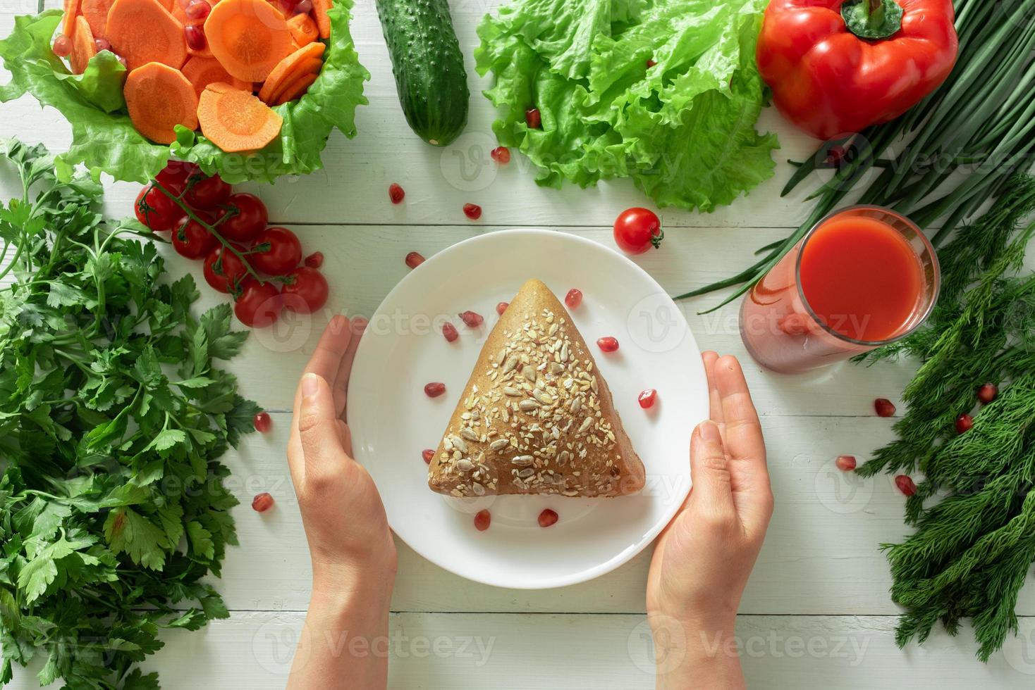 panino grosso sullo sfondo di verdure. mani femminili raggiungono un piatto che mostra la corretta selezione di prodotti per la perdita di peso. foto