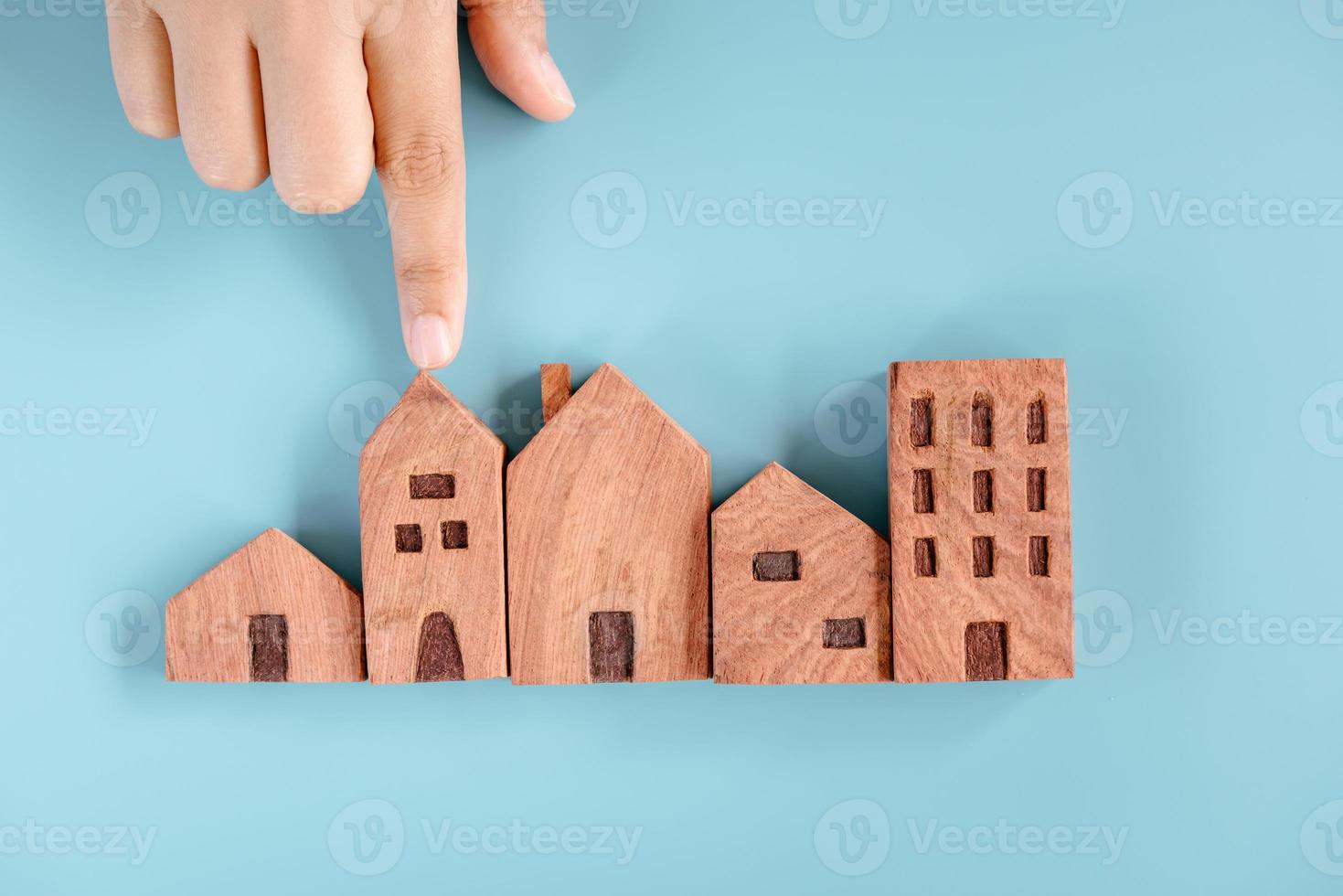 prestito immobiliare immobiliare e concetti di investimento immobiliare, mercato immobiliare aziendale e futuro residenziale. la migliore selezione per la casa di famiglia della vita futura. mano femminile che sceglie casa in miniatura in legno foto