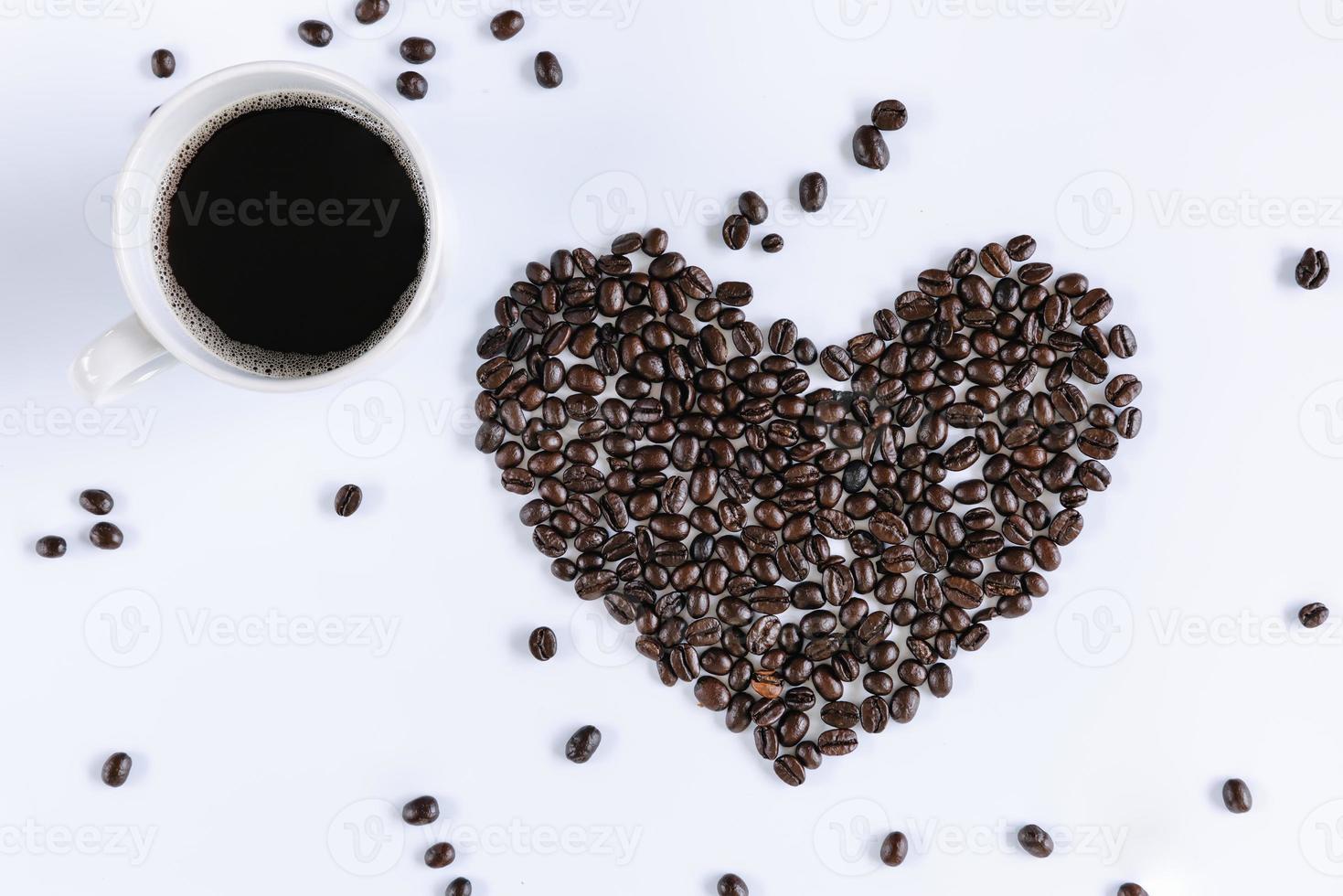tazza di caffè e chicchi di caffè tostati a forma di cuore su sfondo bianco isolato. primo piano di ingredienti di caffè in grani con sfondi di tazza di caffè caldo. concetti di cibo e bevande foto
