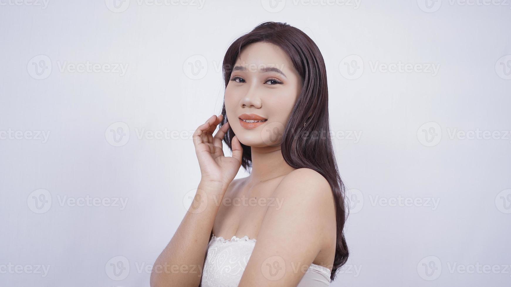 ragazza asiatica compongono sorriso carino mano all'orecchio isolato su sfondo bianco foto