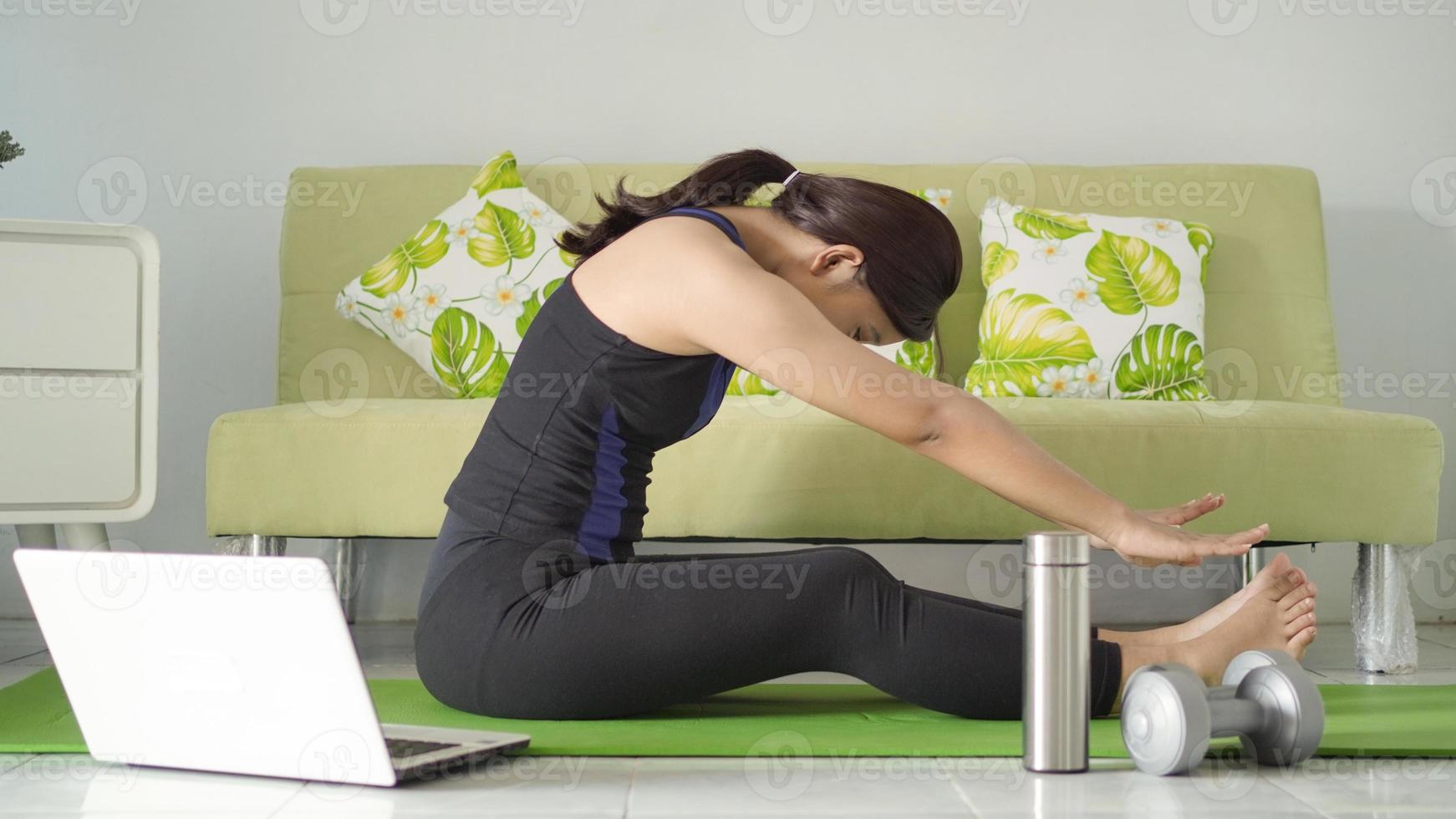 giovane donna che pratica yoga in fase di riscaldamento a casa foto