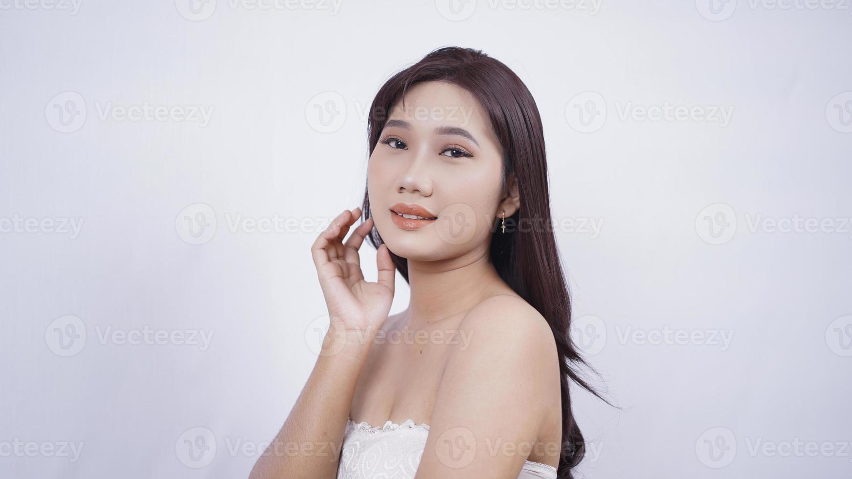 ragazza asiatica compongono sorriso carino mano all'orecchio isolato su sfondo bianco foto