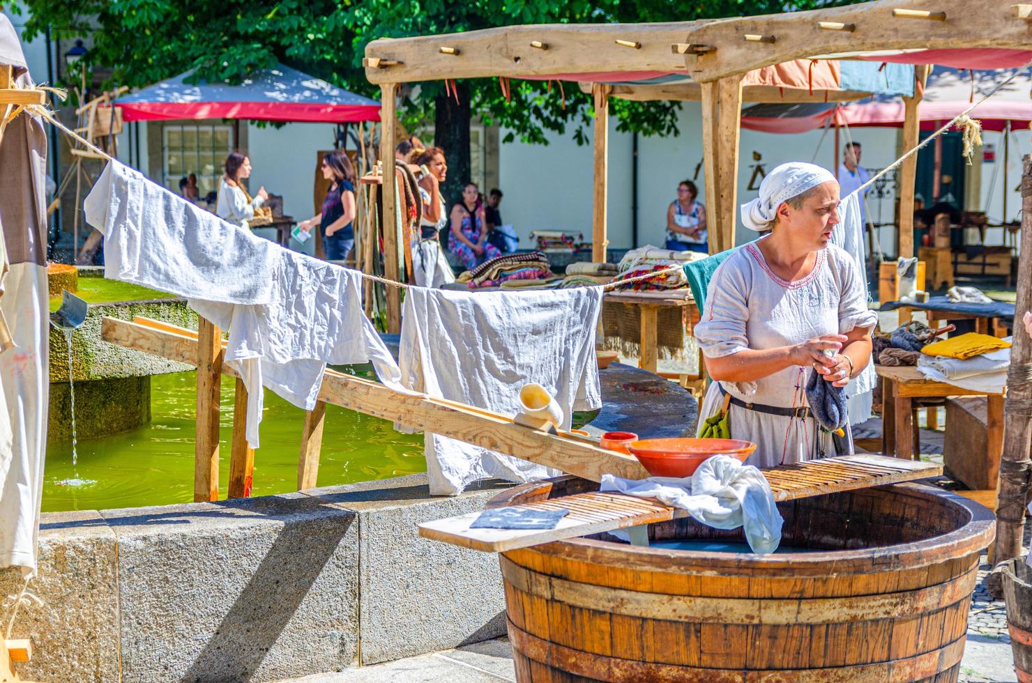 Guimaraes, Portogallo - 24 giugno 2017 serva donna in vecchi vestiti tradizionali che lava la biancheria in botte di legno nel centro storico della città foto