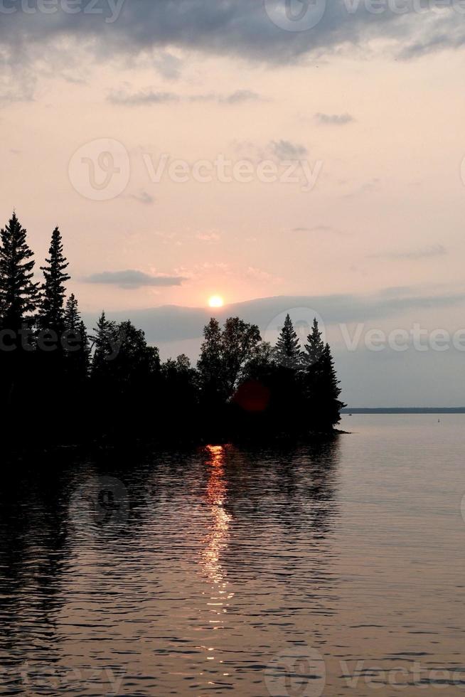 un tramonto che si riflette sul lago limpido nel parco nazionale della montagna di equitazione a manitoba, canada foto