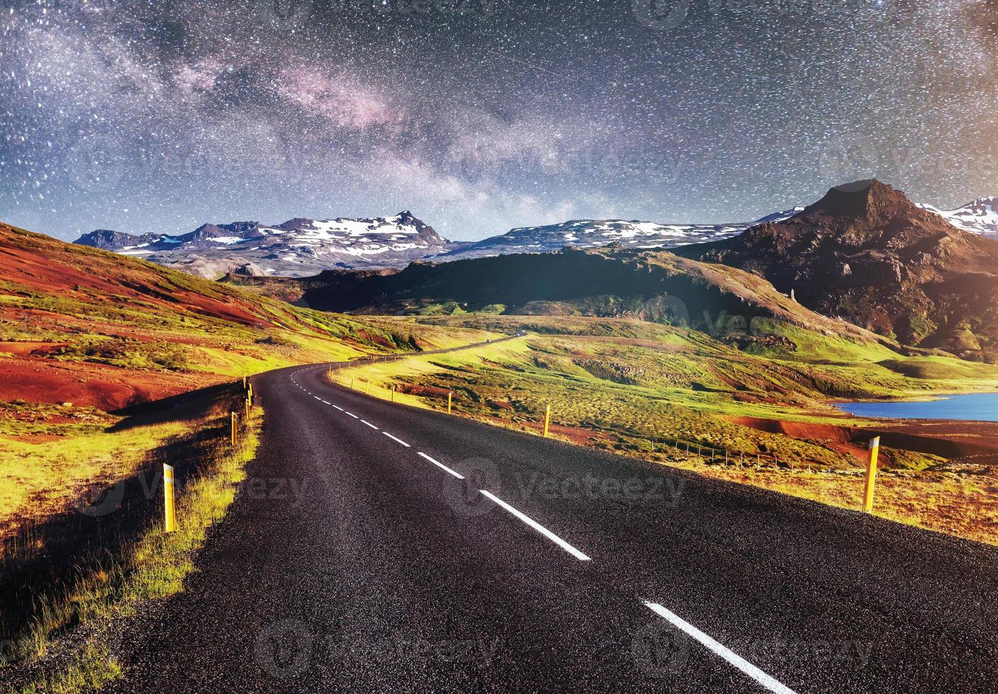 cielo stellato sopra le montagne. la strada asfaltata con segnaletica bianca. bellissimo paesaggio estivo. morbido effetto filtrante. Islanda foto