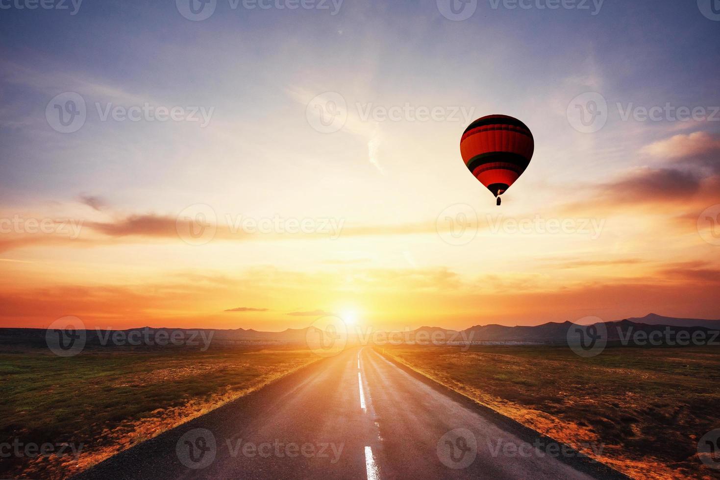 strada asfaltata lungo e palla colorata nel cielo al tramonto foto