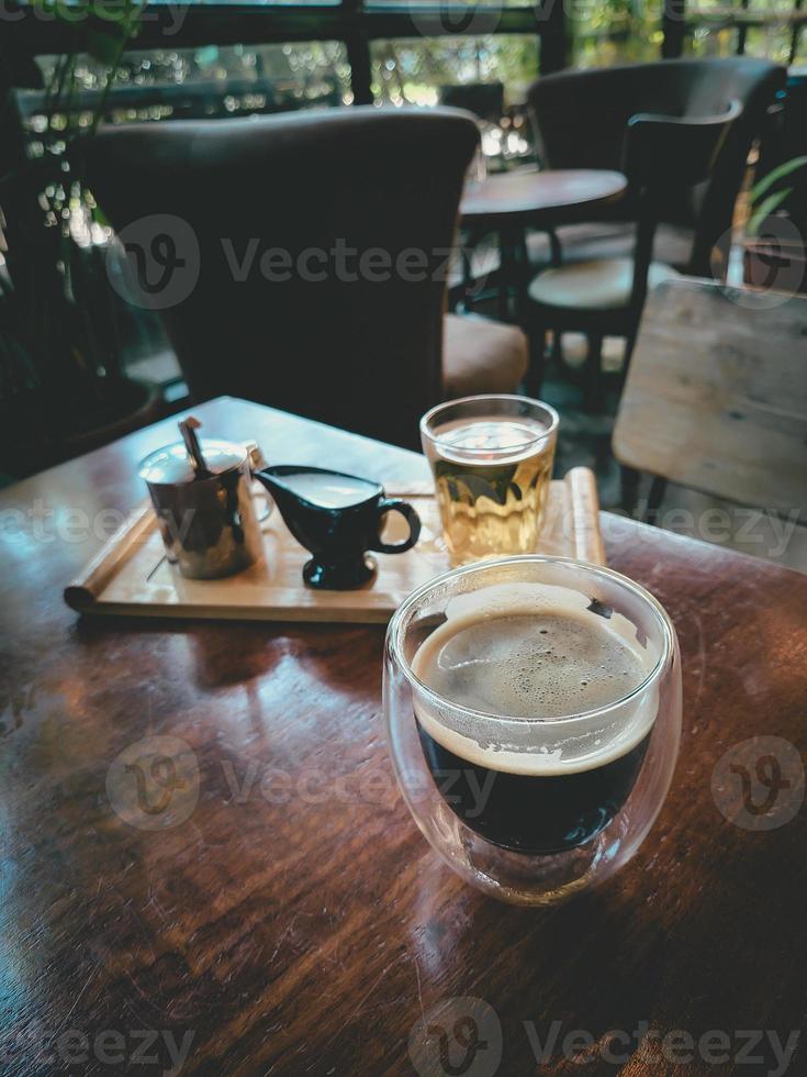 caffè nero su tavola di legno, fondo di legno grigio. bevanda in vetro espresso. bevanda arabica preparata dal barista italiano. tazza di caffeina calda nel caffè del mattino. foto con luce naturale, nessuno.