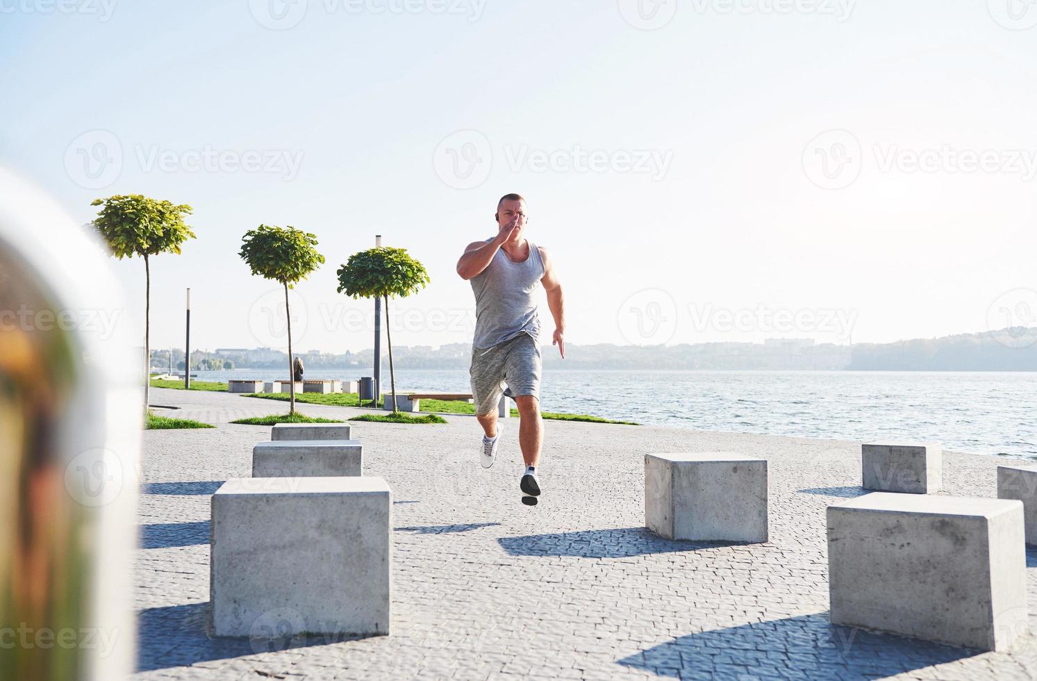 corridore uomo che fa esercizio di stretching, preparandosi per l'allenamento mattutino nel parco foto