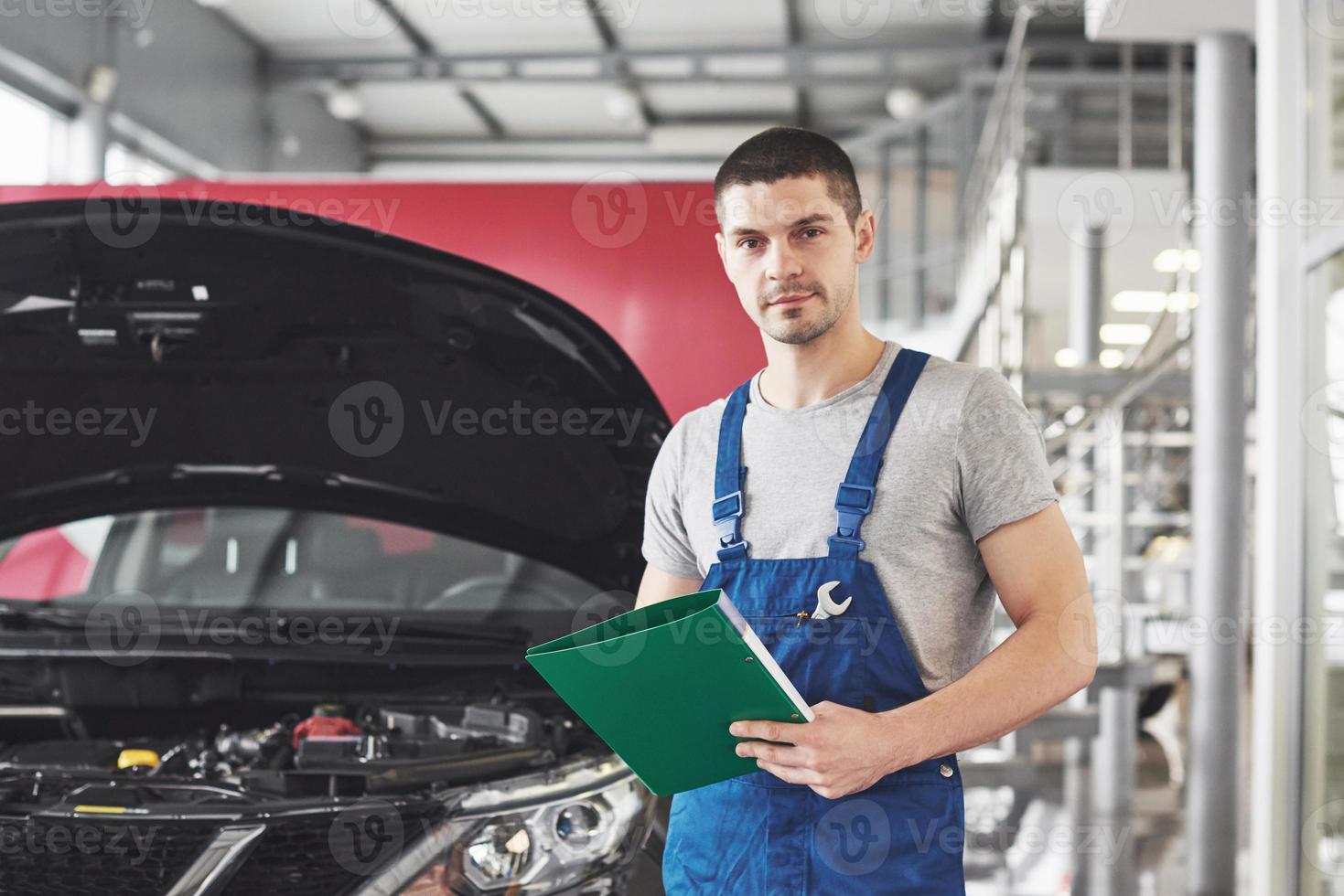 servizio auto, riparazione, manutenzione e concetto di persone - meccanico o fabbro con appunti in officina foto