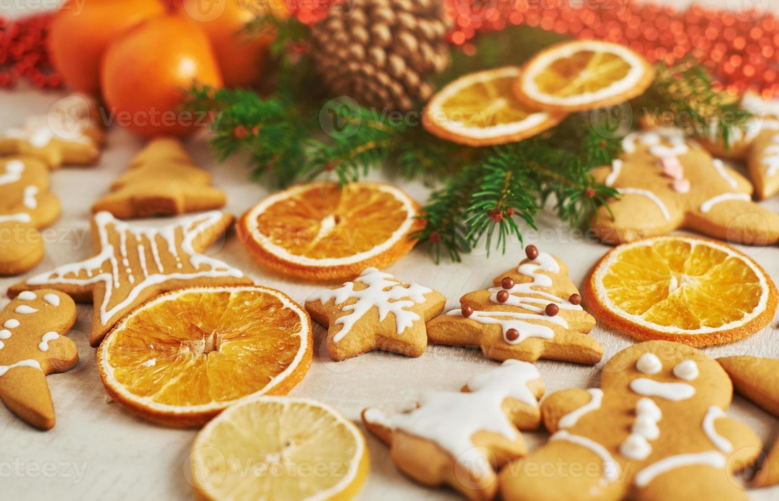 biscotti di pan di zenzero di Natale e arancia secca e spezie sul tavolo bianco. sedie alberi di natale, coni e decorazioni natalizie foto