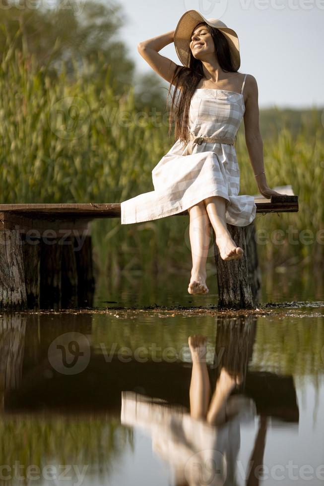 giovane donna rilassante sul molo di legno al lago calmo foto