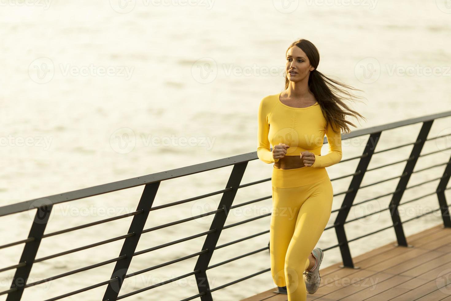 giovane donna che corre sul molo lungo il fiume foto