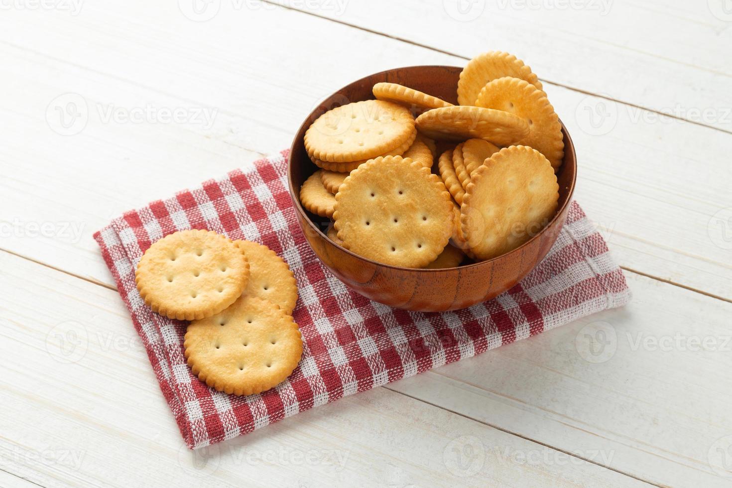 biscotti cracker arrotondati in una ciotola di legno con tovaglia su sfondo bianco tavolo in legno foto