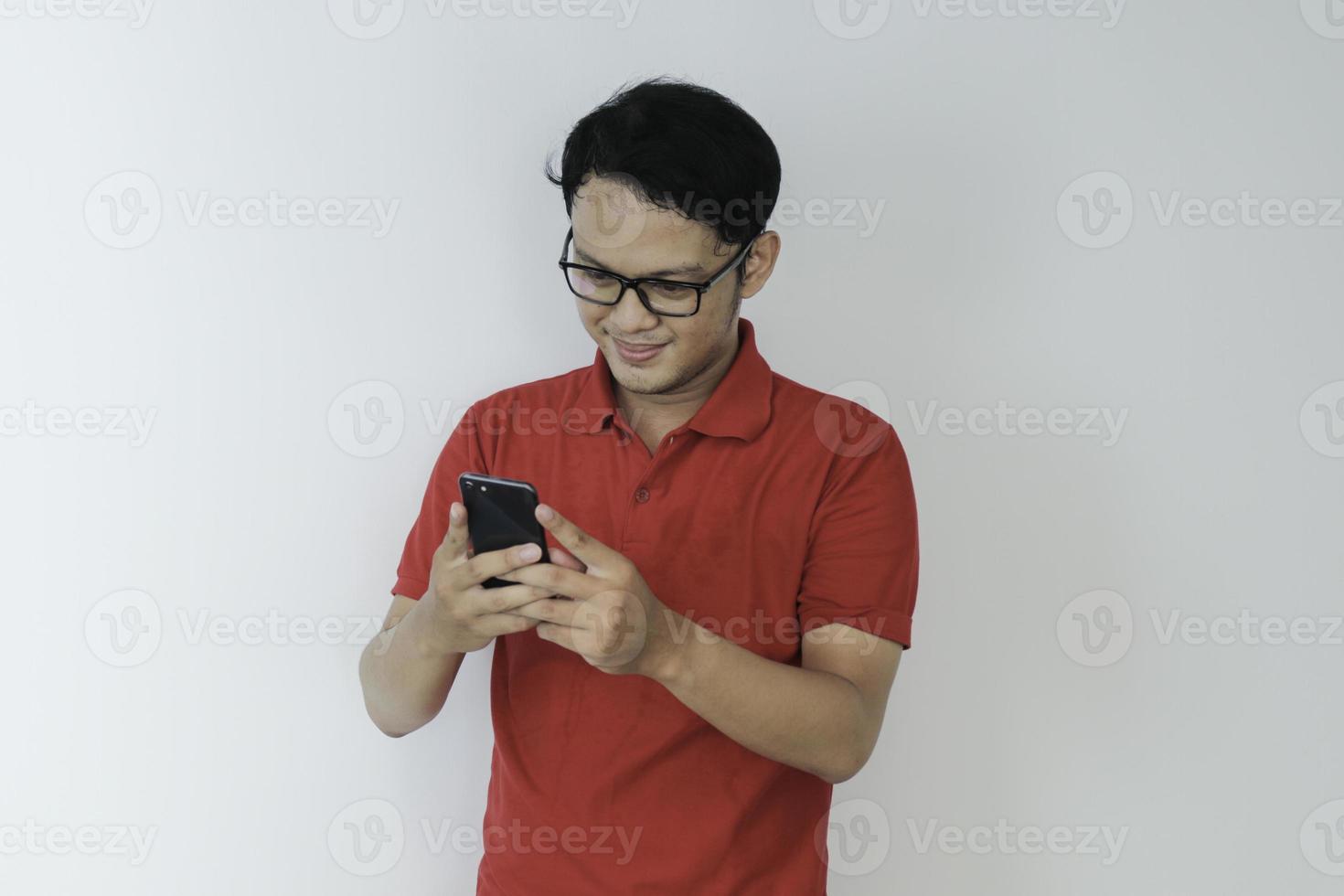 il giovane uomo asiatico intelligente è felice e sorridente quando utilizza lo smartphone in background foto