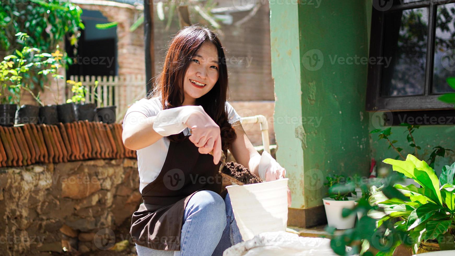 donna asiatica preparare un posto per piantare con vaso foto
