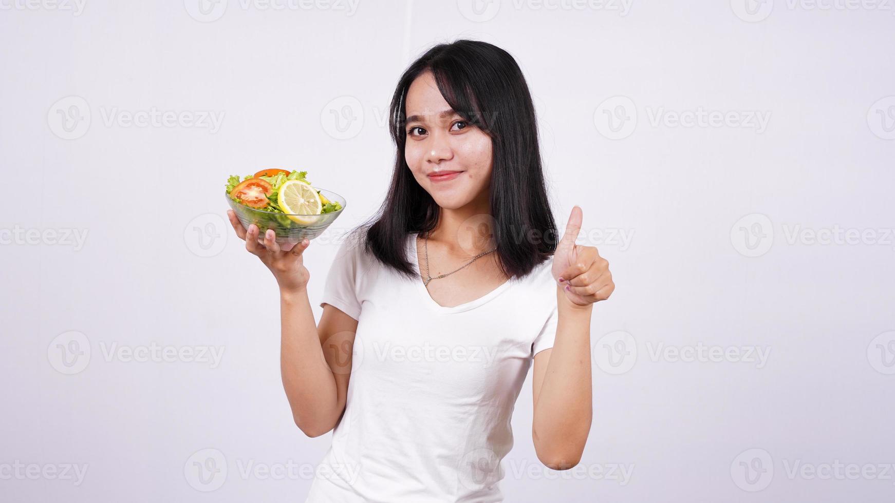 donne asiatiche e dito ok in una ciotola di insalata di verdure miste fresche con sfondo bianco isolato foto