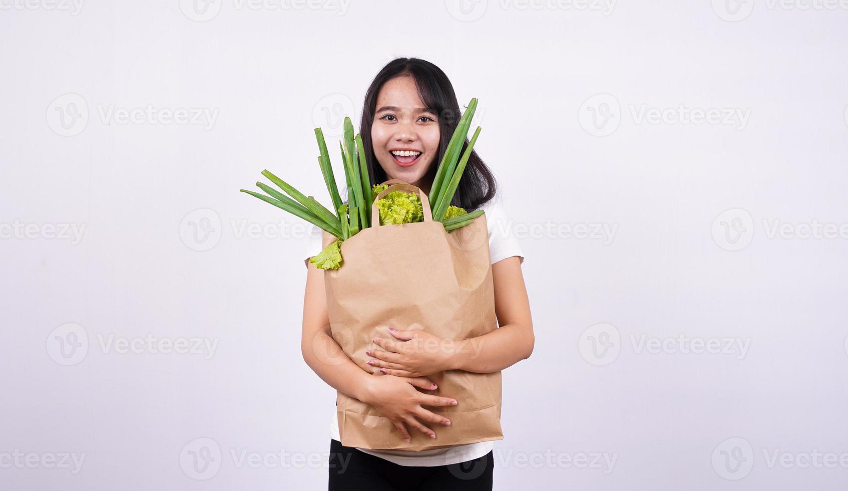 bella donna asiatica sorridente con sacchetto di carta di verdure fresche con sfondo bianco isolato foto