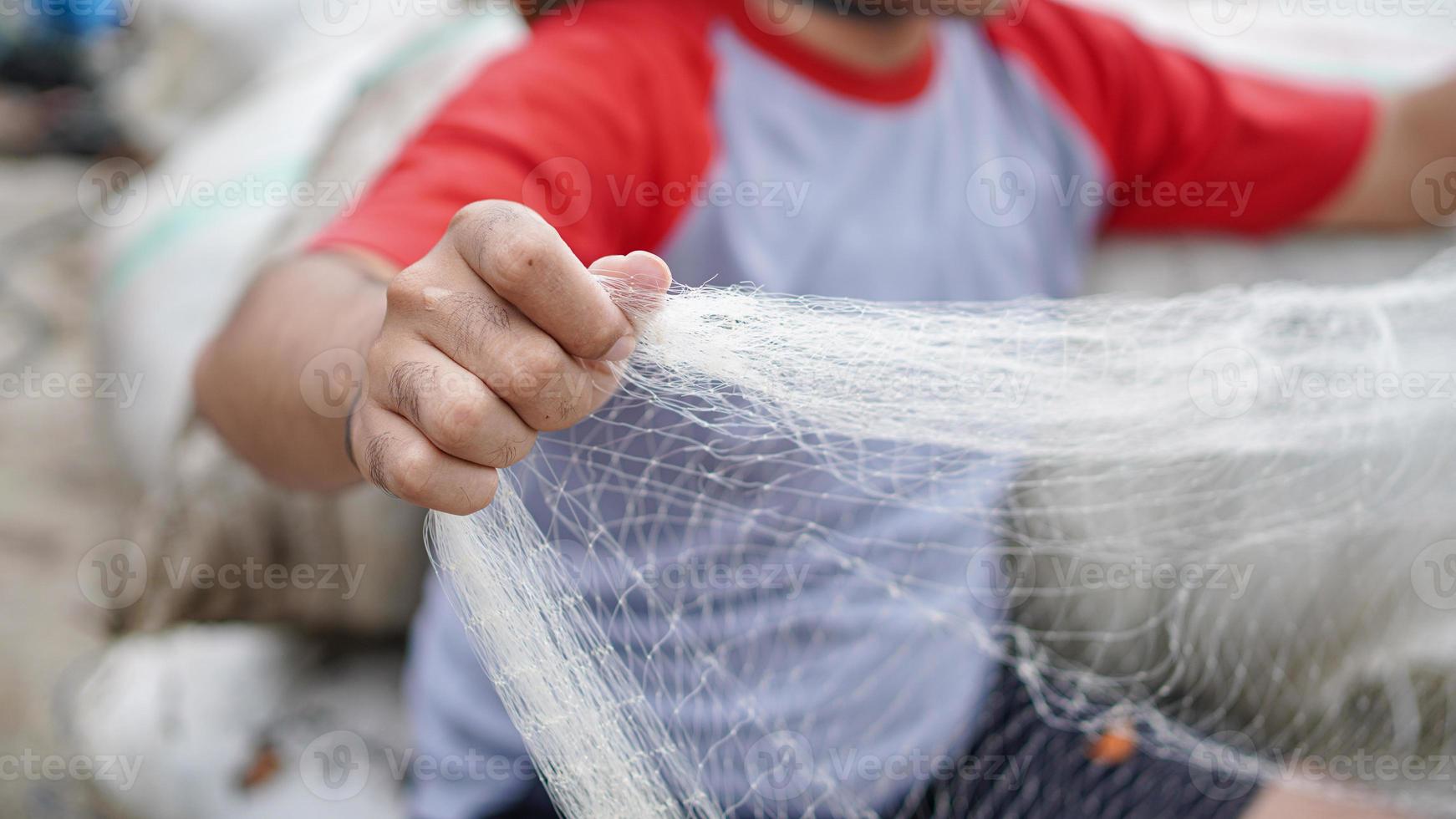 ritratto di un giovane pescatore maschio che prepara una rete da pesca in spiaggia foto