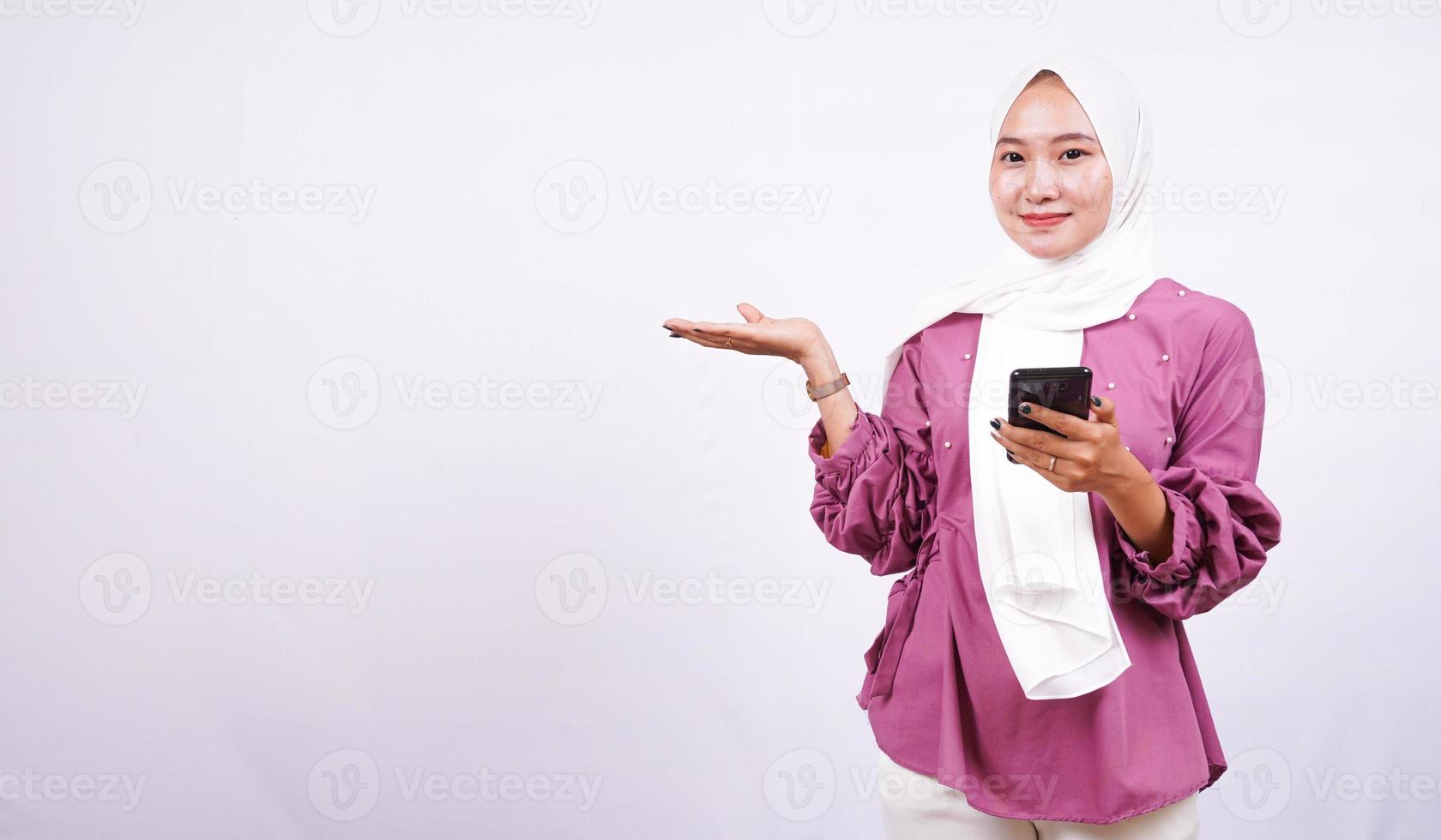 belle donne hijab che puntano l'area e tengono il telefono isolato su sfondo bianco foto