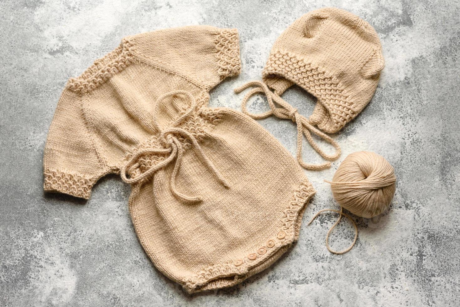 vestiti beige lavorati a maglia per bambini su uno sfondo di cemento bianco foto