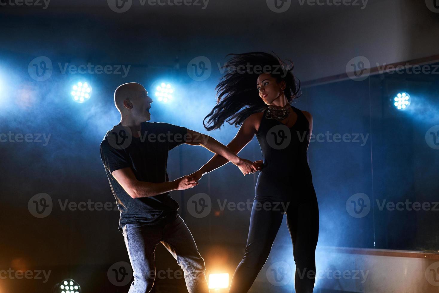 abili ballerini si esibiscono nella stanza buia sotto la luce e il fumo del concerto. coppia sensuale che esegue una danza contemporanea artistica ed emotiva foto