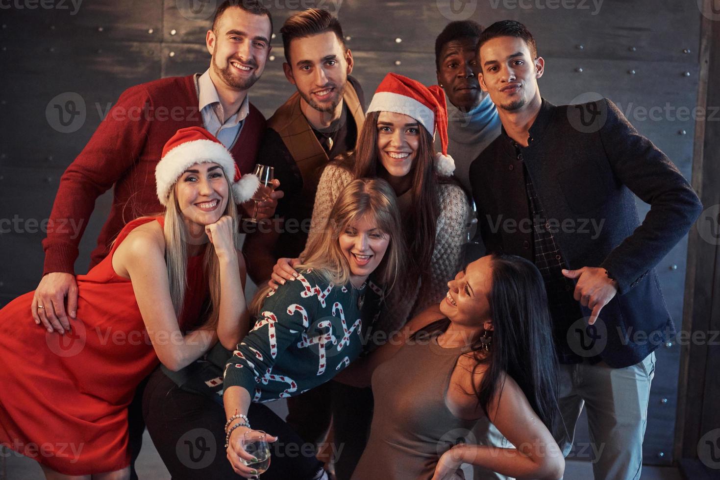 il nuovo anno sta arrivando. gruppo di allegri giovani multietnici in cappelli di Babbo Natale alla festa, in posa concetto di persone con uno stile di vita emotivo foto