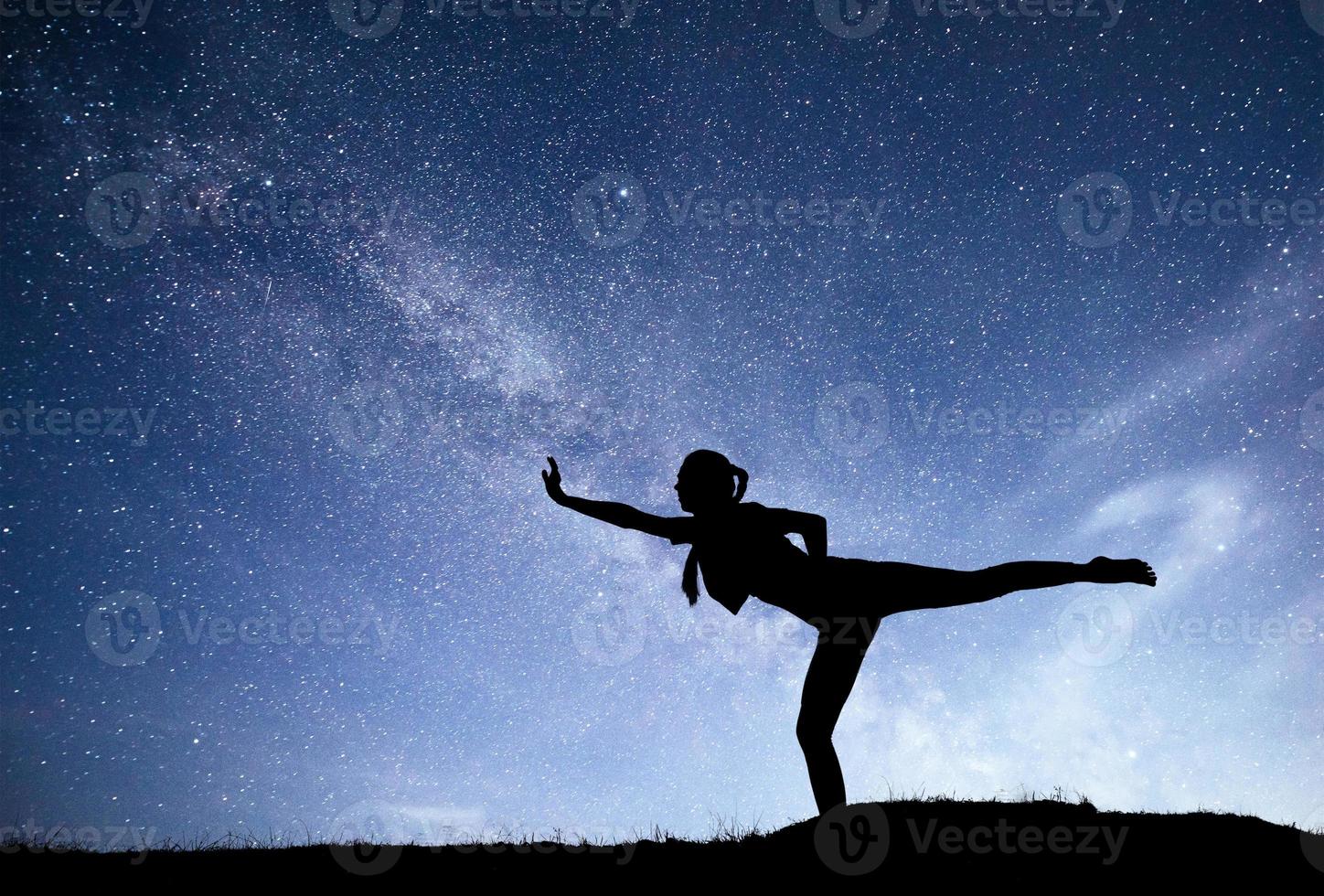 Via Lattea con silhouette di una donna in piedi che pratica yoga sulla montagna. bellissimo paesaggio con ragazza meditando contro il cielo stellato notturno con via lattea. incredibile galassia. universo foto