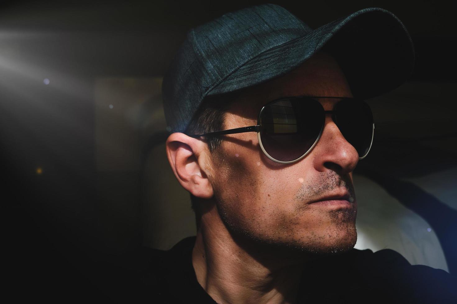 uomo con berretto e occhiali da sole che si fa un selfie nell'ombra foto