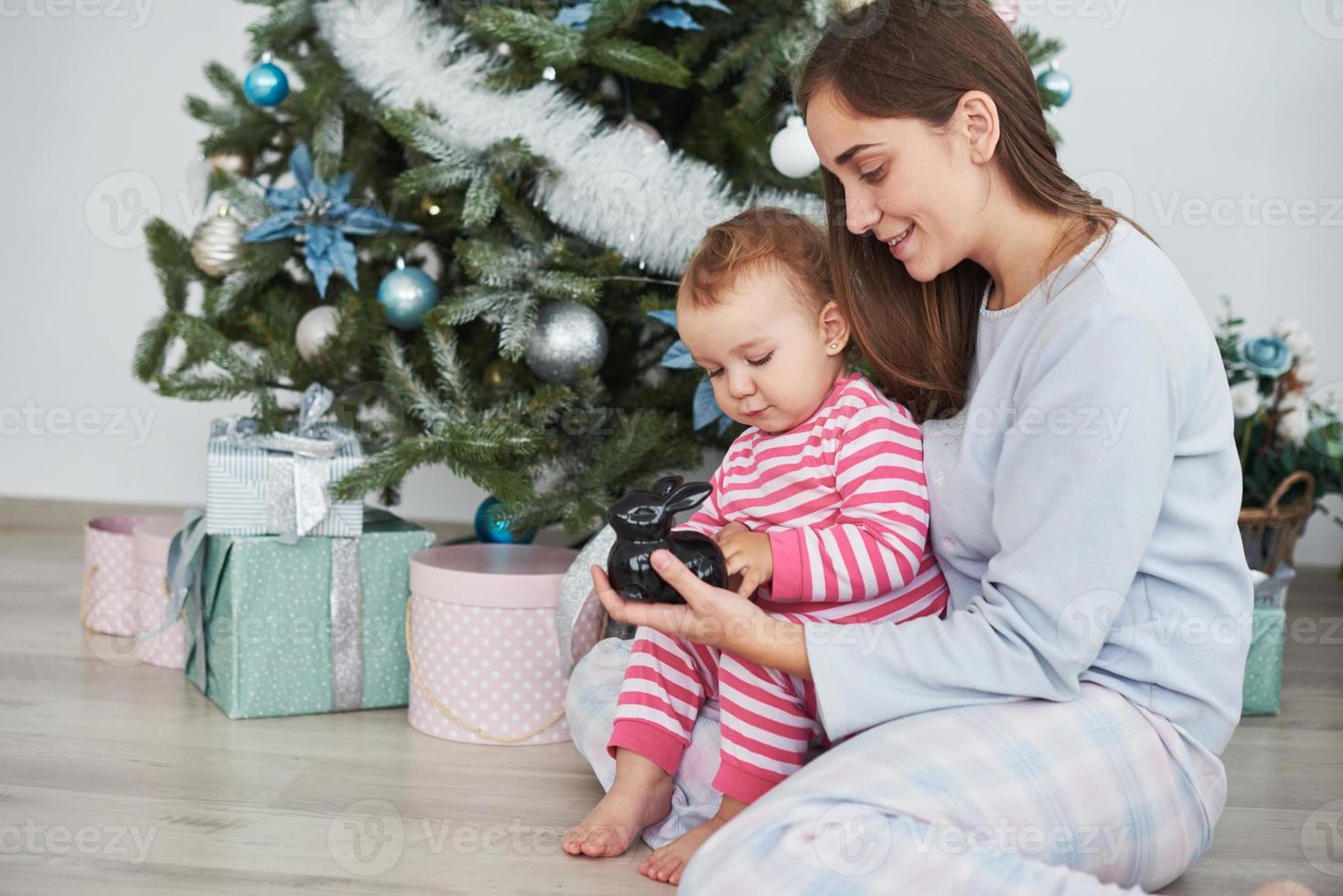 famiglia felice madre e figlia la mattina di natale all'albero di natale con regali foto