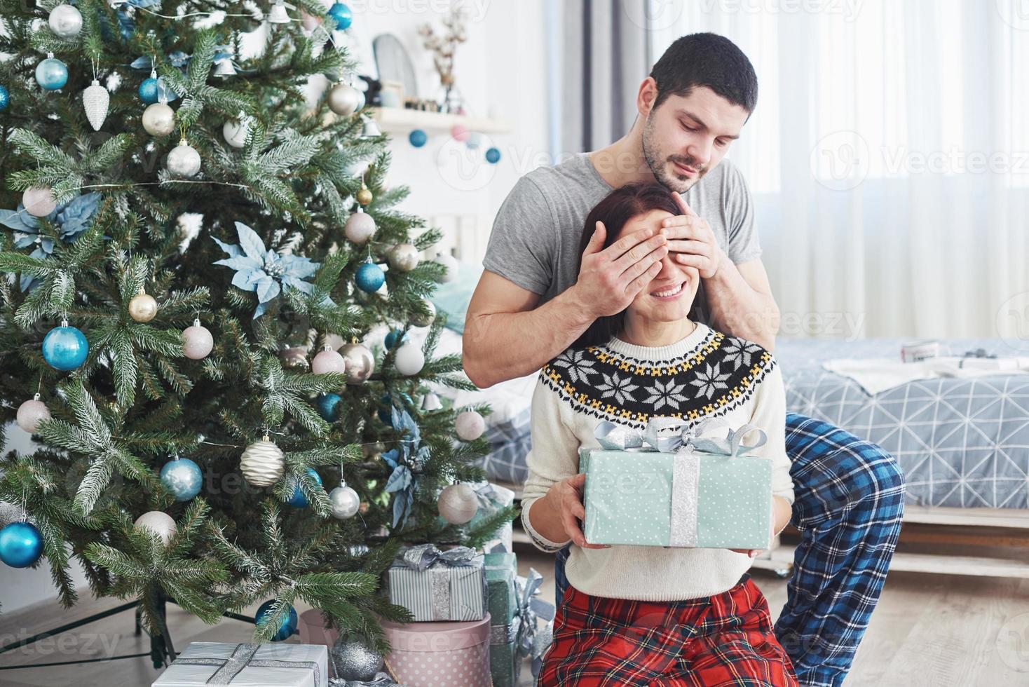 giovane coppia che celebra il natale. un uomo ha presentato improvvisamente un regalo a sua moglie. il concetto di felicità e benessere familiare foto