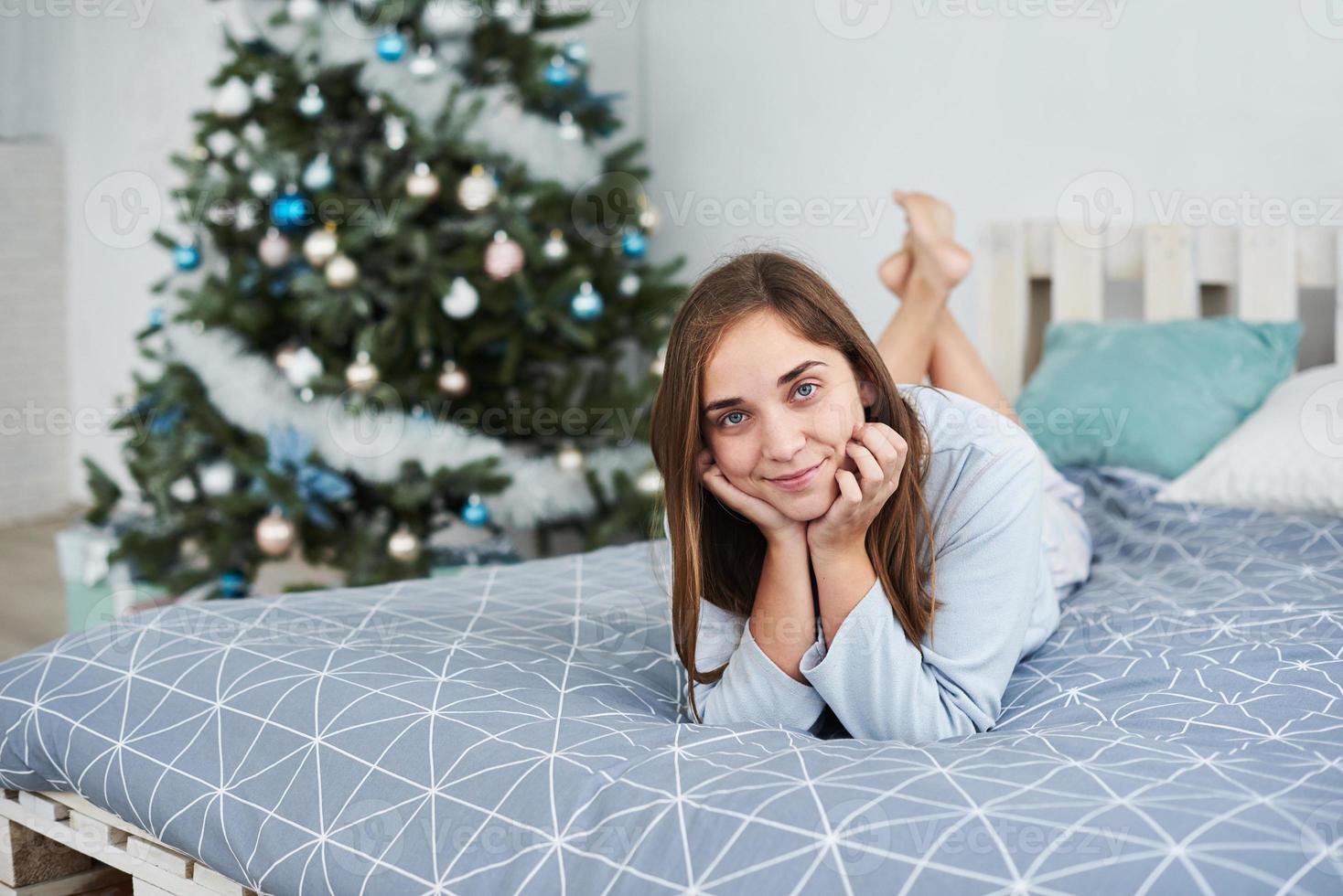 bella ragazza giace su un letto in pigiama la mattina di natale foto