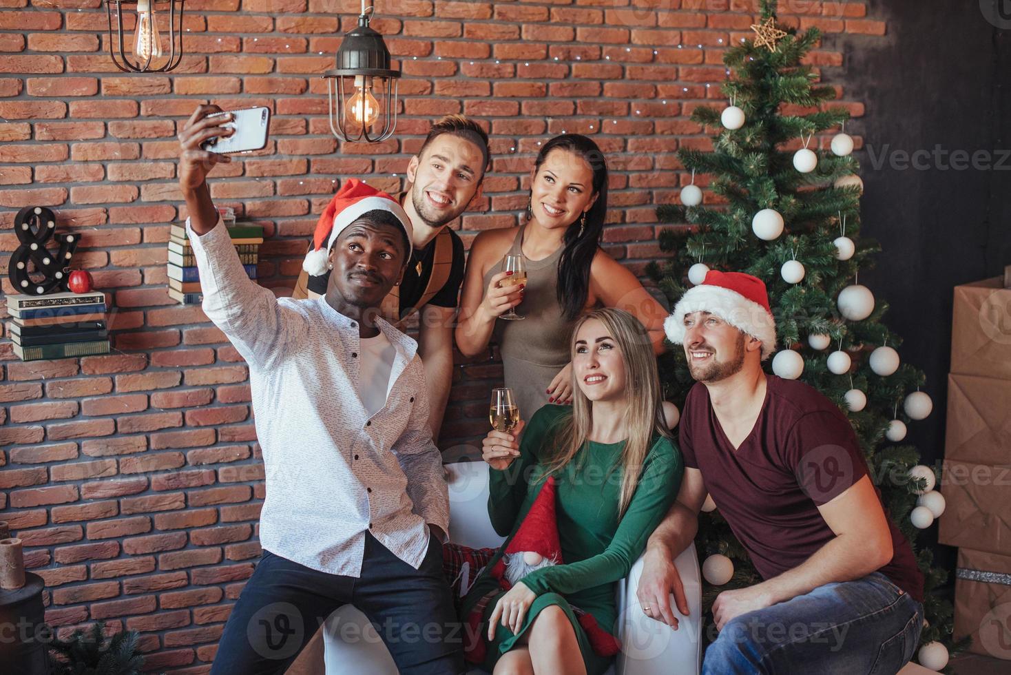 gruppo di amici che celebrano insieme le vacanze di capodanno al chiuso foto