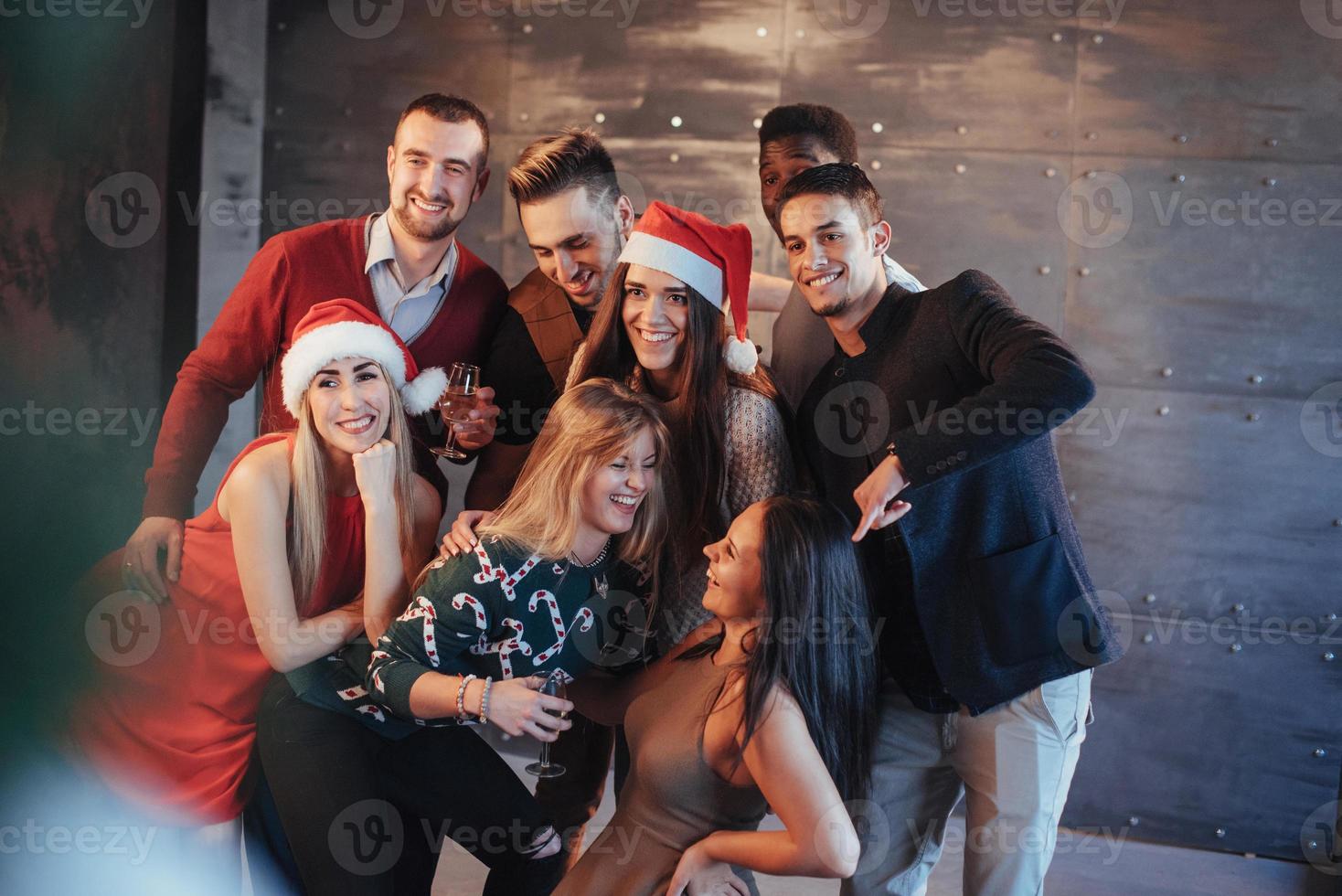 il nuovo anno sta arrivando. gruppo di allegri giovani multietnici in cappelli di Babbo Natale alla festa, in posa concetto di persone con uno stile di vita emotivo foto