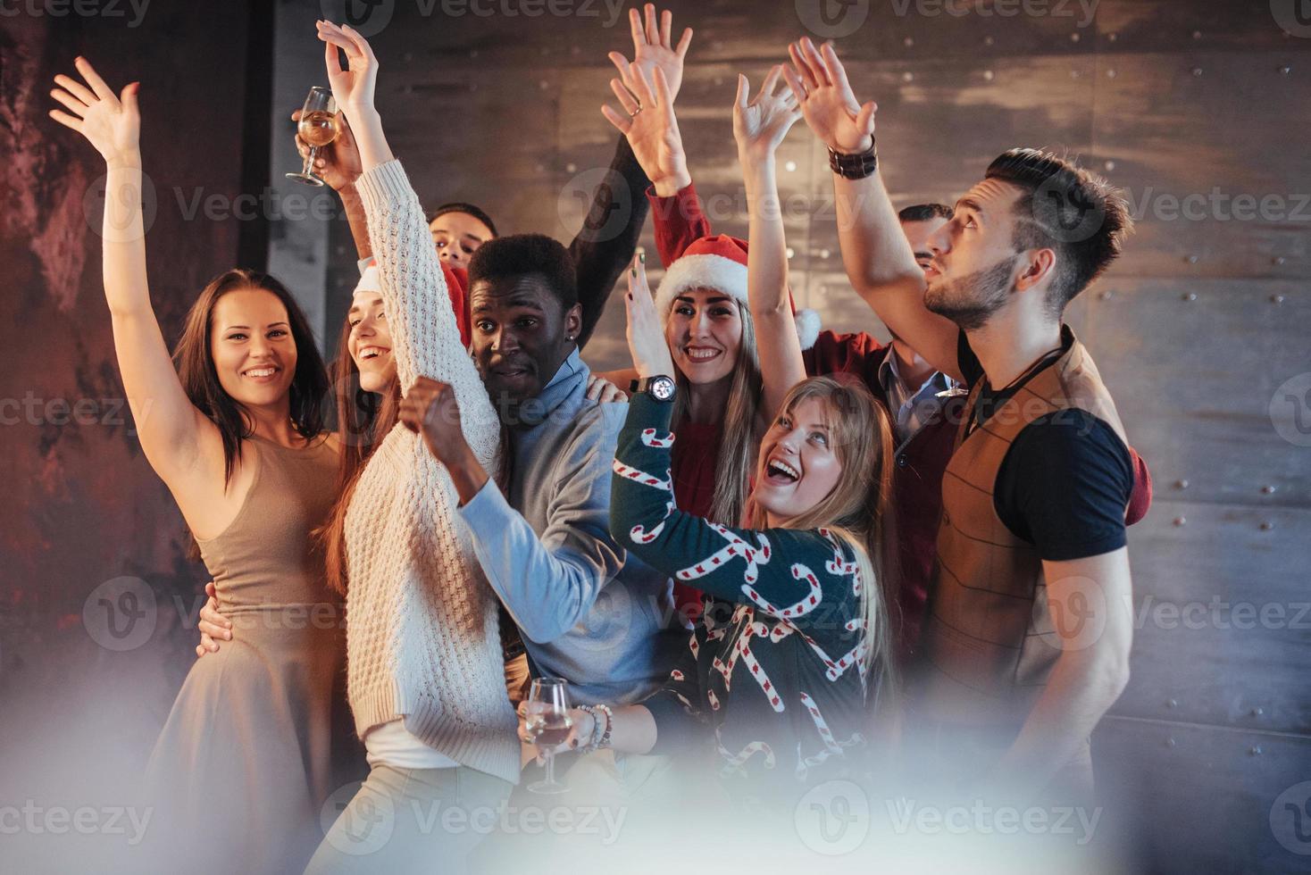 festa con gli amici. amano il natale. gruppo di giovani allegri che trasportano stelle filanti e flauti di champagne che ballano alla festa di capodanno e sembrano felici. concetti sullo stile di vita insieme foto