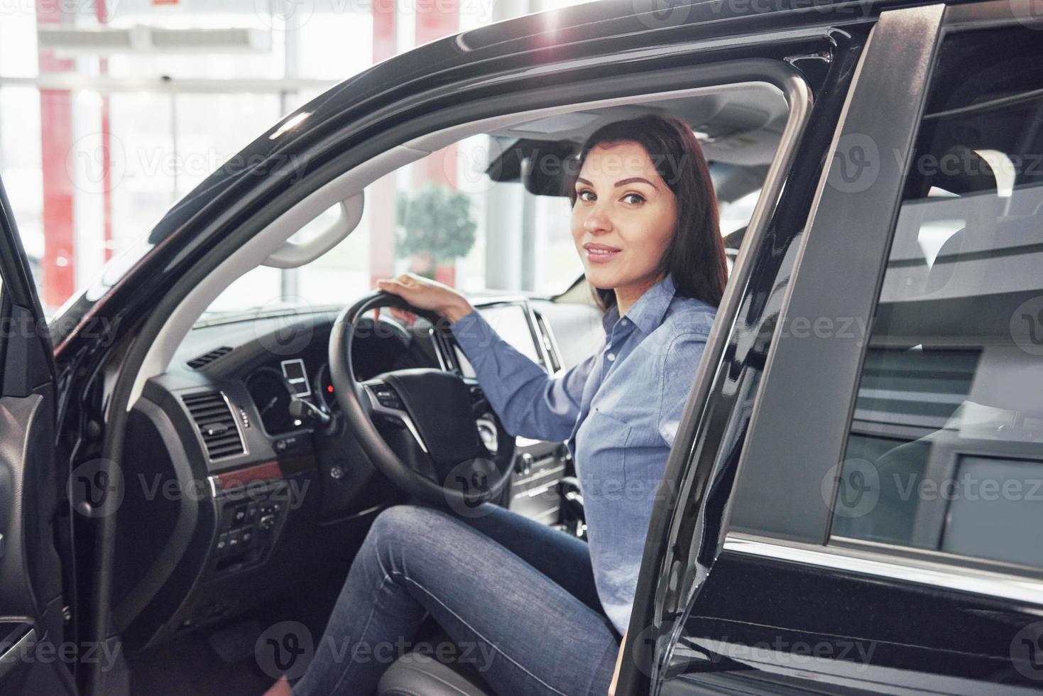 affari automobilistici, vendita di automobili, consumismo e concetto di persone - donna felice che prende la chiave dell'auto dal rivenditore in un salone di auto o in un salone foto