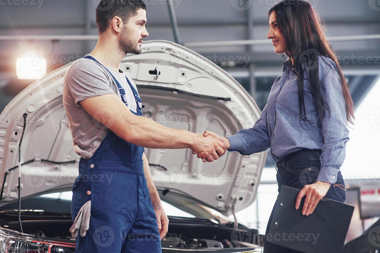marito meccanico di auto e cliente donna stipulano un accordo per la riparazione dell'auto foto