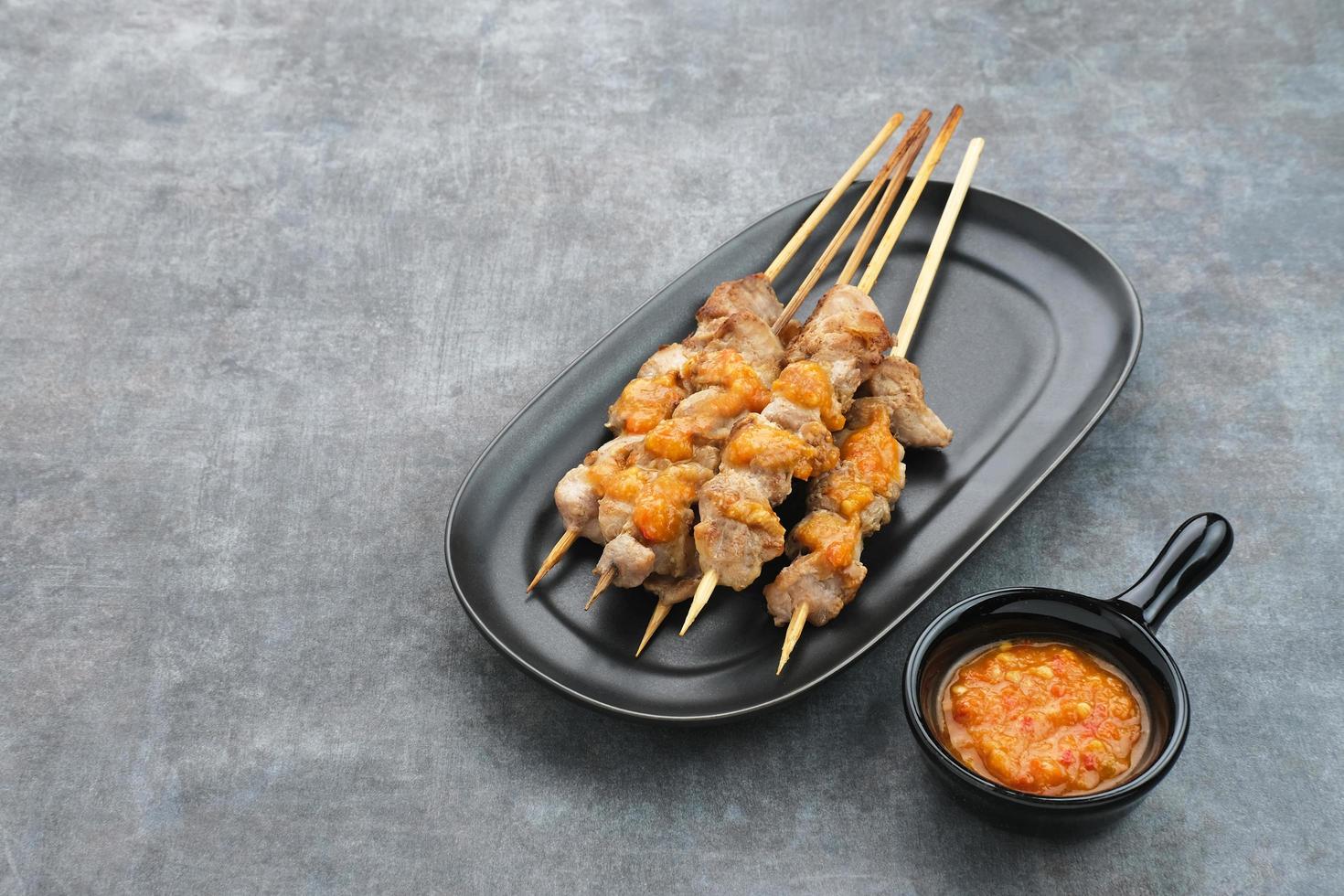 sate taichan, satay di pollo alla griglia senza salsa di arachidi o salsa di soia. servito su piatto con salsa di peperoncino. foto