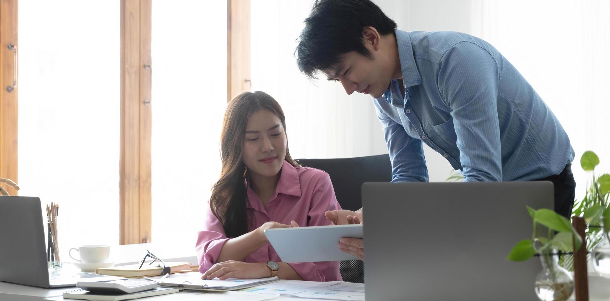 imprenditore uomo d'affari asiatico e donna d'affari che discutono di un nuovo progetto di business in tablet in una riunione moderna in un ufficio moderno, concetto casual business asiatico. foto