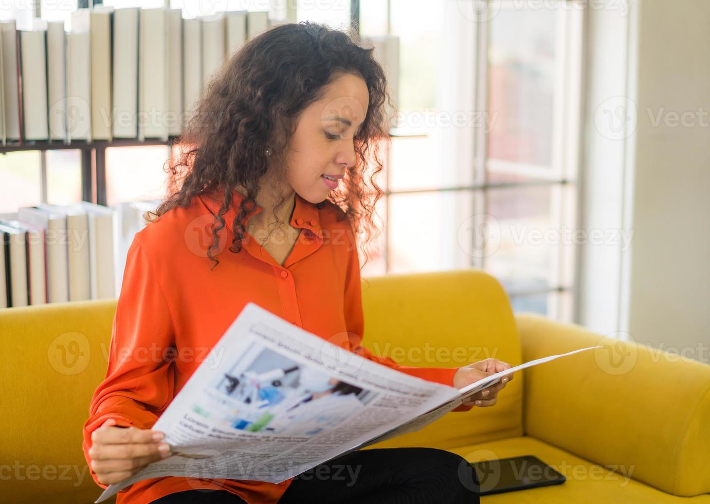 America latina donna che legge il giornale sul divano foto