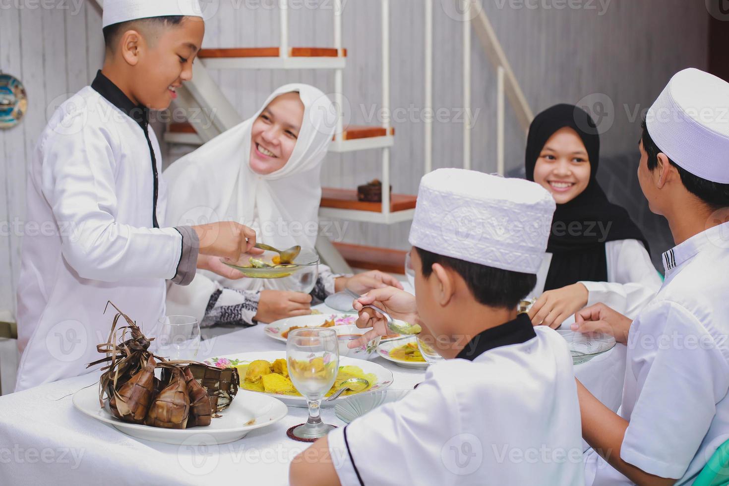 felice famiglia musulmana che celebra eid mubarak mangiando insieme nella sala da pranzo foto